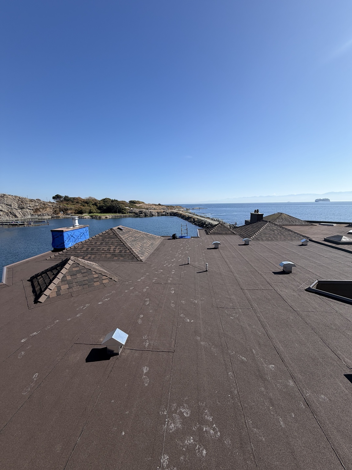 Large flat roof with membrane surface, vents and shingled roof sections