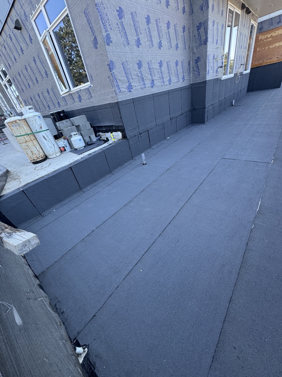 Membrane surface and wall upstands beside a work area with materials and equipment